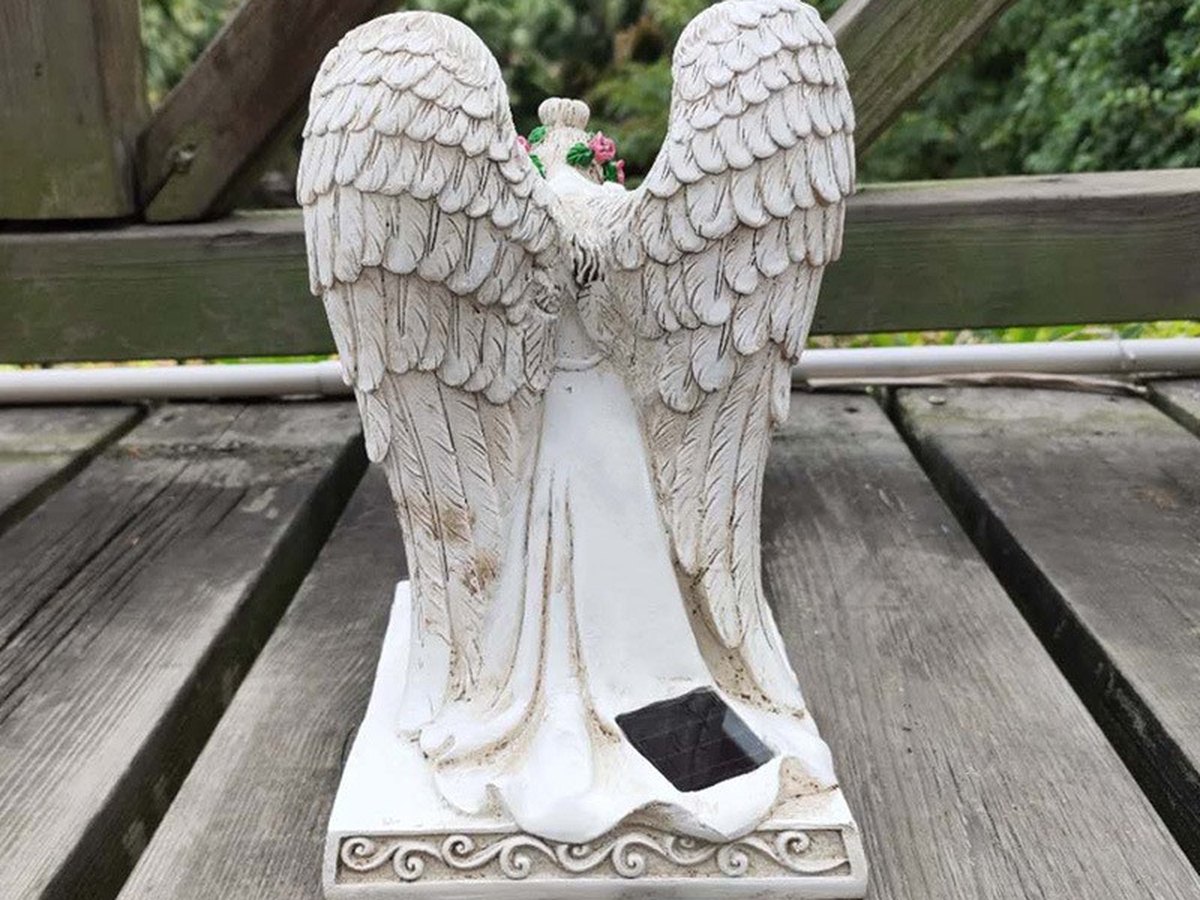 White angel wing memorial statue standing on a wooden deck